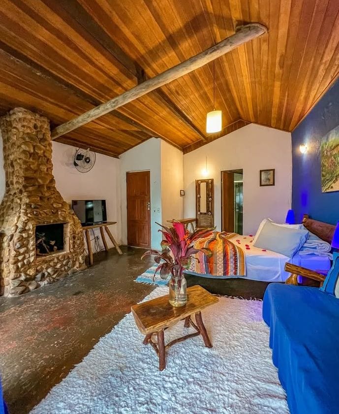 Chalé Azul — quarto com paredes azul-noite, lareira de pedra e mural pintado